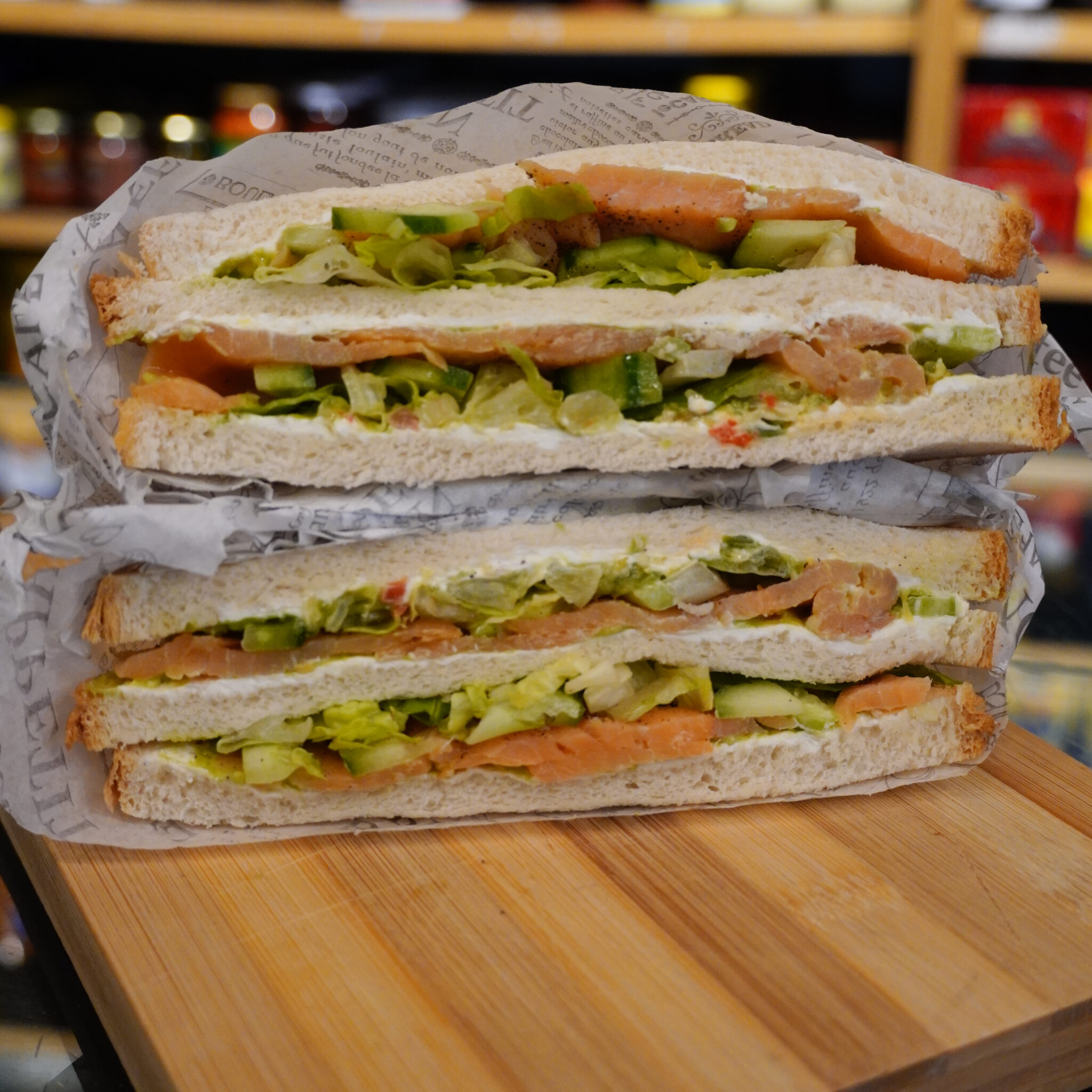 Club sandwich au saumon fumé, concombre et crudités, présenté en double étage sur une planche en bois