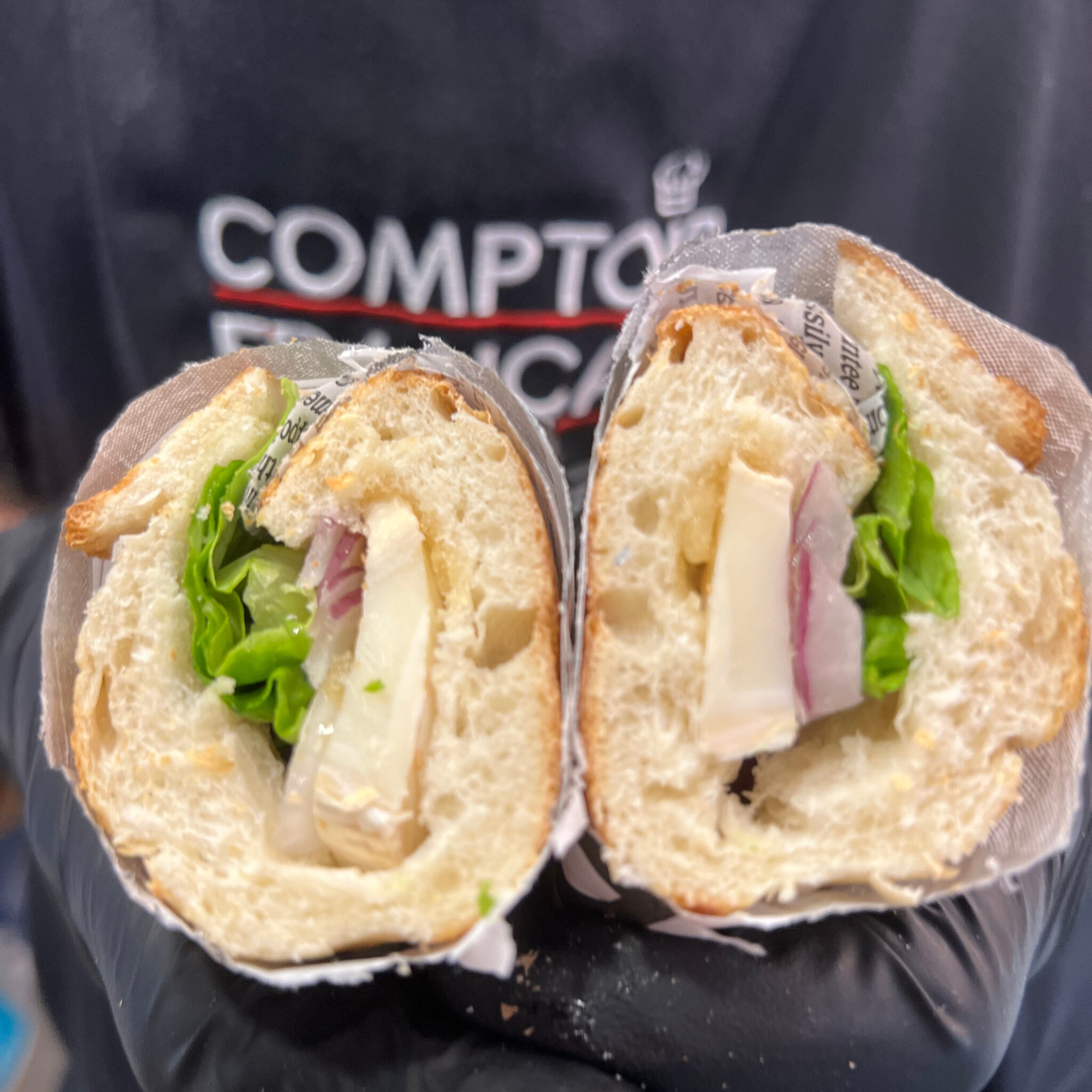 Sandwich au brie français, charcuterie et laitue, coupé en deux sur baguette